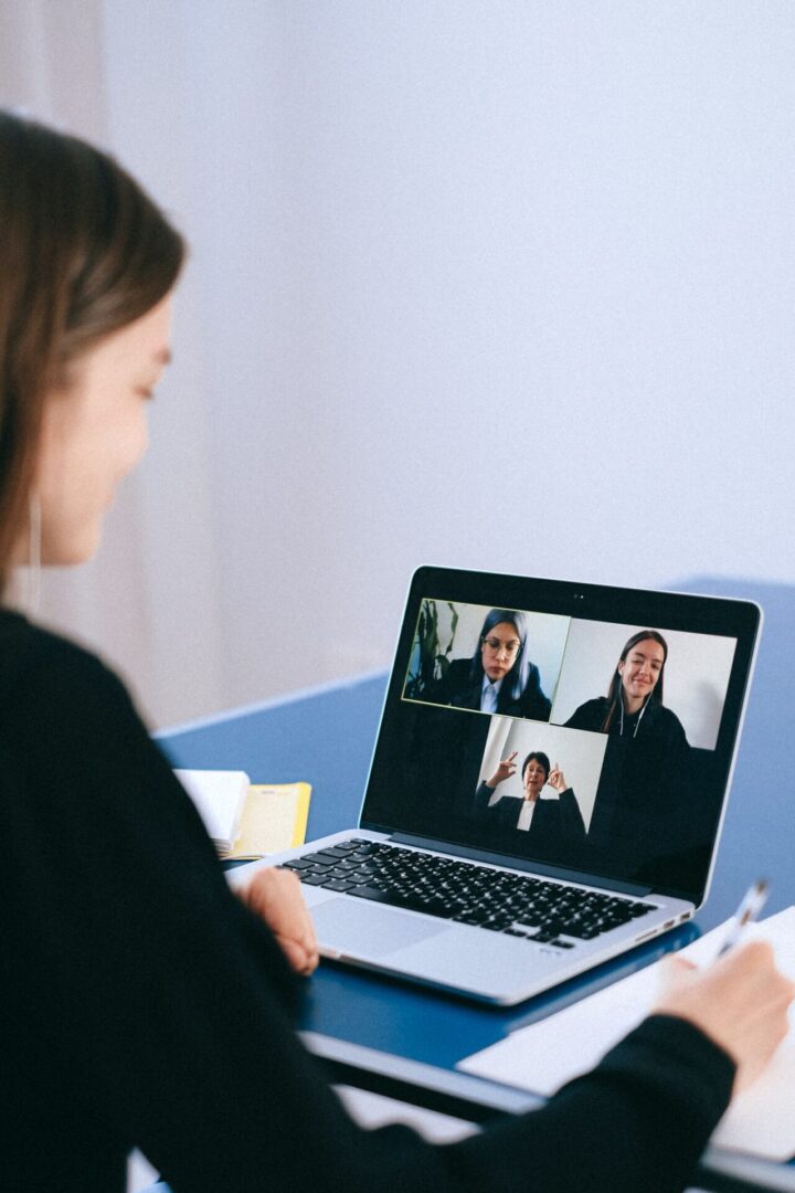 a woman writing in a notebook while on video conference